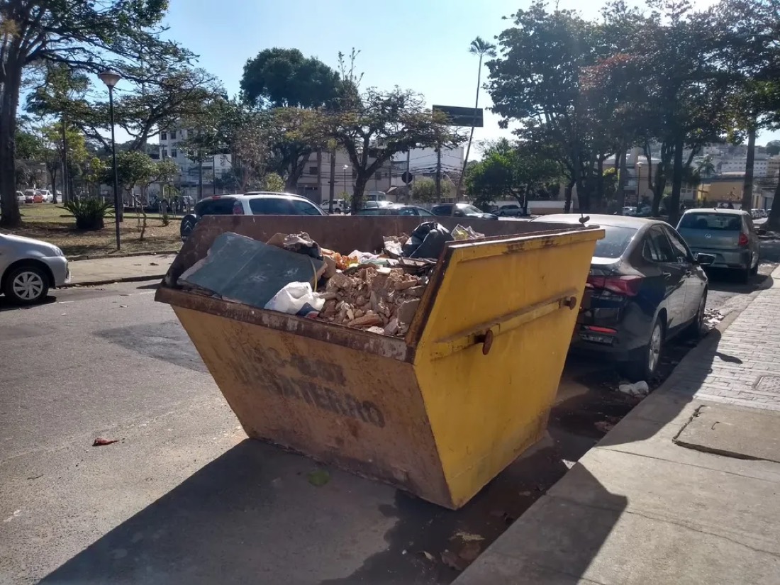 Caçamba amarela cheia de entulho na rua, em Goiânia